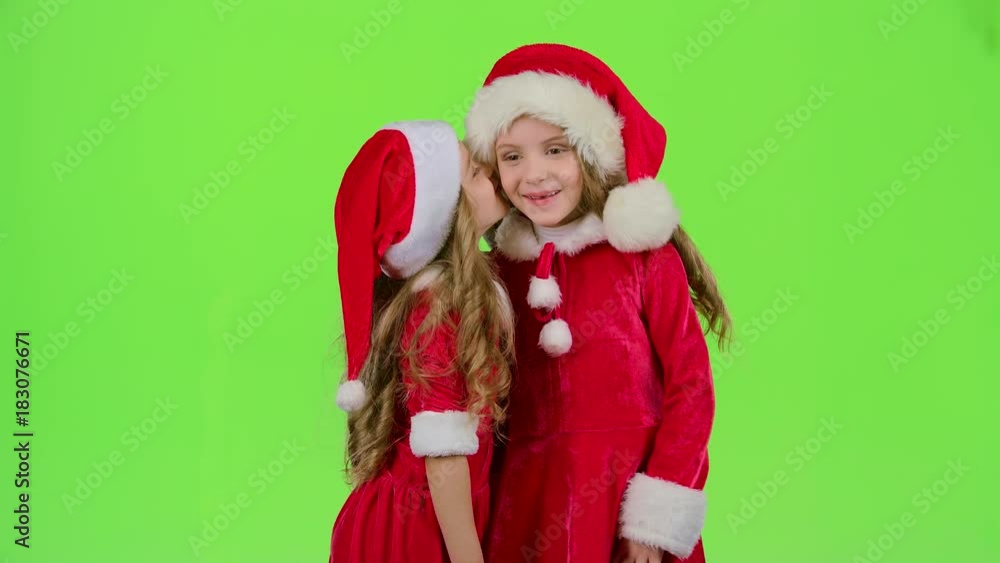 Two baby girls in New Year costumes tell each other secrets. Green screen. Slow motion Two baby girls in New Year costumes tell each other secrets. Green screen. Slow motion