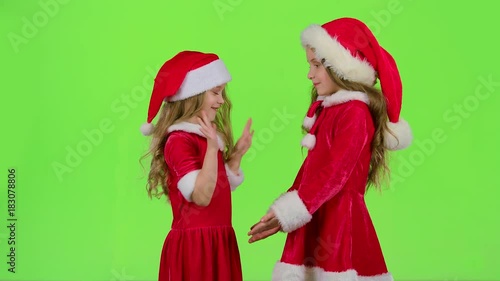 Children in red suits play New Year's games, smile and have fun. Green screen. Slow motion photo