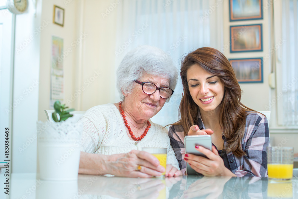 Young woman showing something on mobile phone to grandmother. Young woman showing something on mobile phone to grandmother.