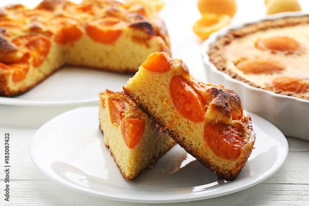 Slices of apricot pie with fruits on white wooden table Slices of apricot pie with fruits on white wooden table