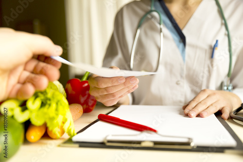 Vegetable diet nutrition and medication concept. Nutritionist is giving prescription and offers healthy vegetables diet.