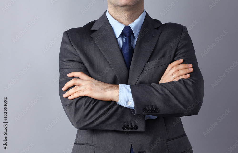 Businessman standing with arms crossed, isolated on gray background Businessman standing with arms crossed, isolated on gray background