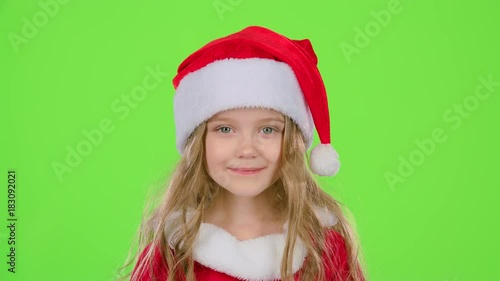 Baby in a beautiful suit and a red New Year's cap smiles. Green screen. Slow motion photo