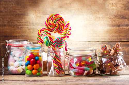 Colorful candies, lollipops, marshmallows and gingerbread cookies  in a glass jars