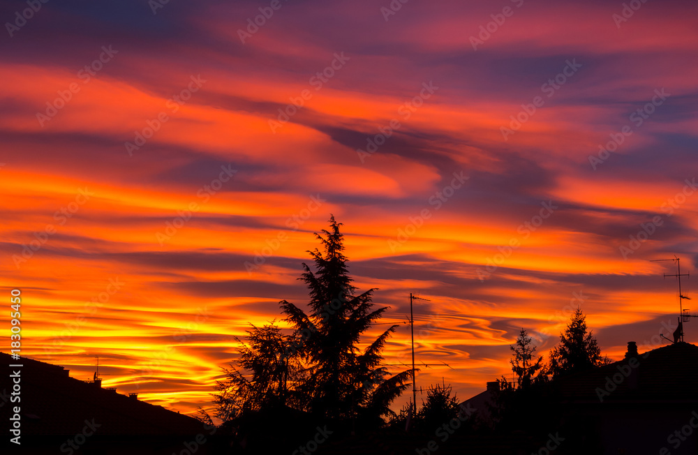 Fiery sunset during fall season. Colored clouds creating clouds and abstract shapes in sky