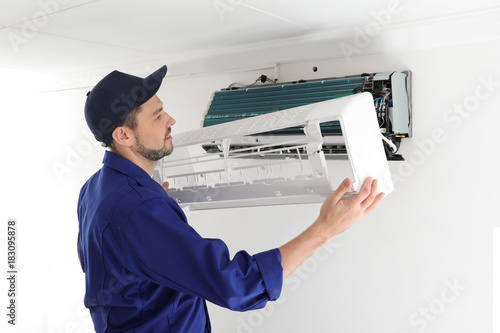 Male technician repairing air conditioner indoors photo