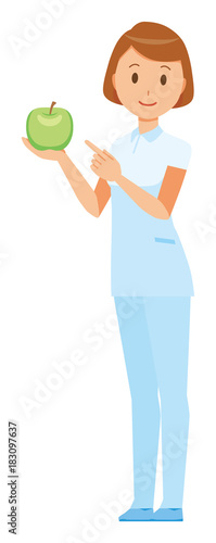 A female nurse wearing a white uniform has a green apple