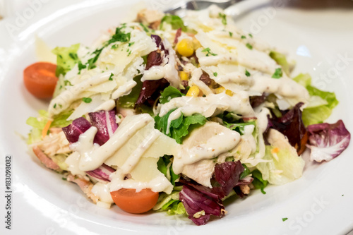 Caesar salad with roasted chicken breast, parmesan cheese, lettuce leaf, cherry tomatoes, corn and cheese sauce