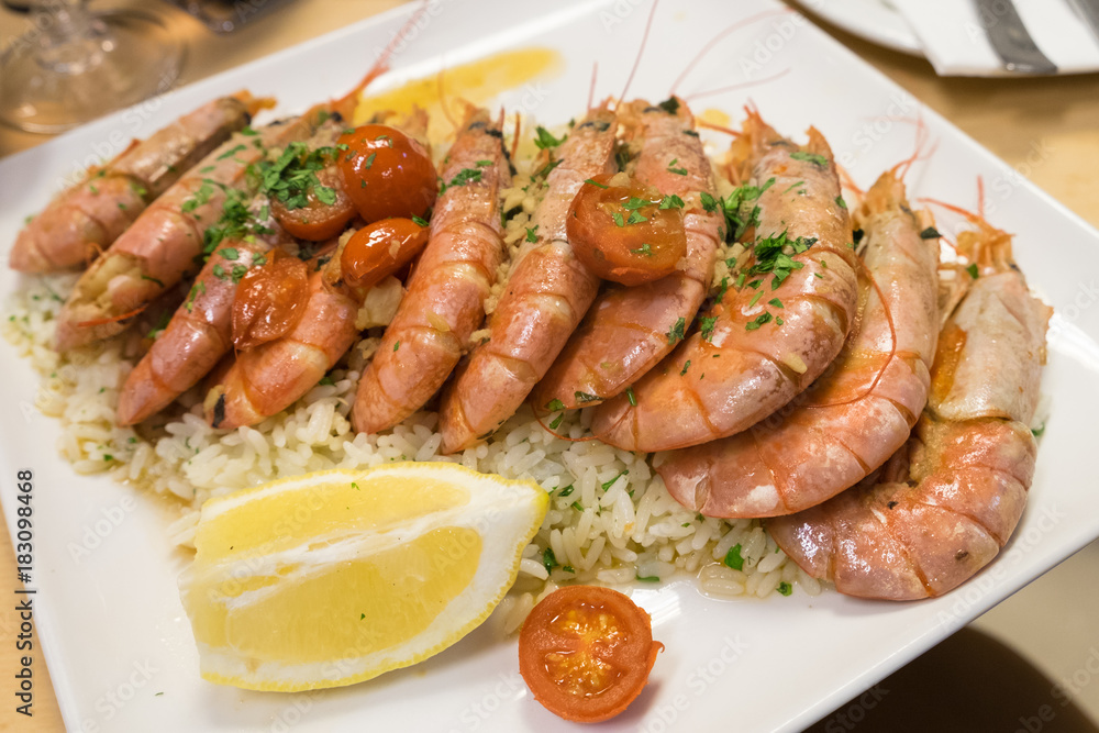 Seafood risotto (rice) with grilled prawns and cherry tomatoes