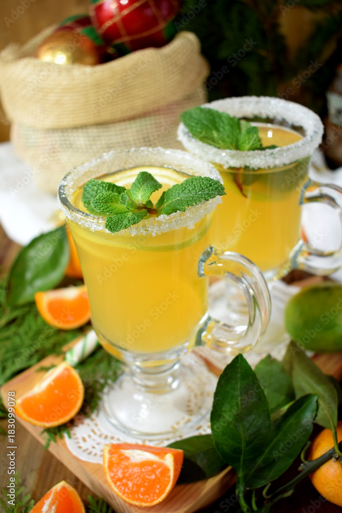 Fototapeta premium Yellow cocktail in an Irish mug decorated with sugar border and mint surrounded by Christmas attributes
