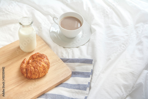 Bed breakfast with coffee cup, croissants and milk in bed, cozy relaxing morning coffee, holidays and winter concept