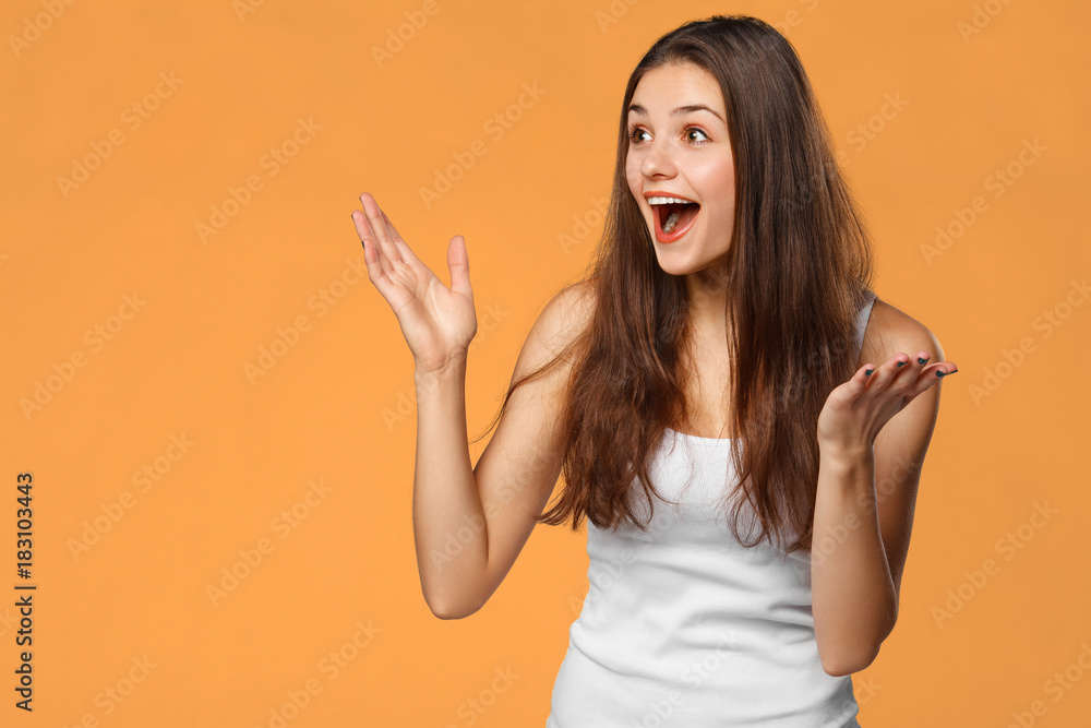 Surprised happy beautiful woman looking sideways in excitement, isolated on orange background Surprised happy beautiful woman looking sideways in excitement, isolated on orange background