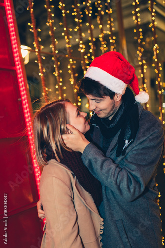 Beautiful young couple in love enjoying Christmas or New Year night on a city street.  © hedgehog94