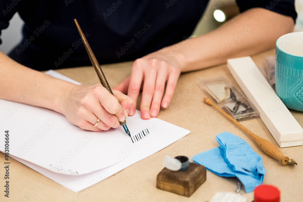 arts and crafts, hobby, talent concept. caucasian woman calligrapher is writing with old style quill and beautiful blue inks on the table with all equipment for art arts and crafts, hobby, talent concept. caucasian woman calligrapher is writing with old style quill and beautiful blue inks on the table with all equipment for art
