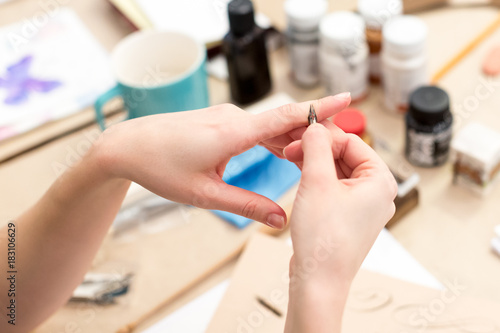 arts and crafts  creativity  handmade concept. close up of two wonderful female arms with delicate thin fingers and tidy manicure  she is holding quill for calligraphy