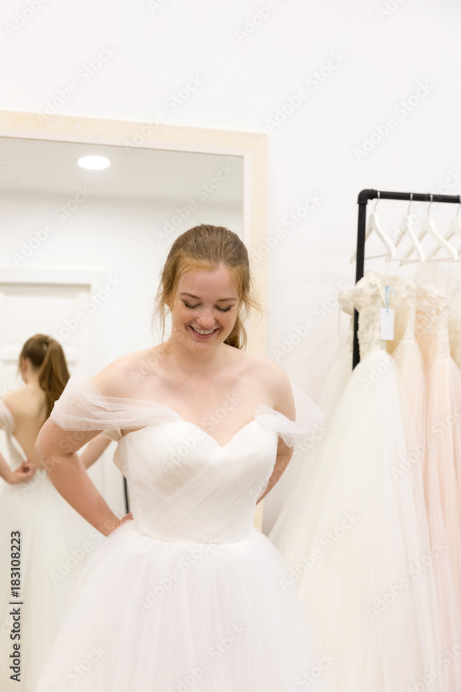 Woman try on wedding bride dress in the fitting room