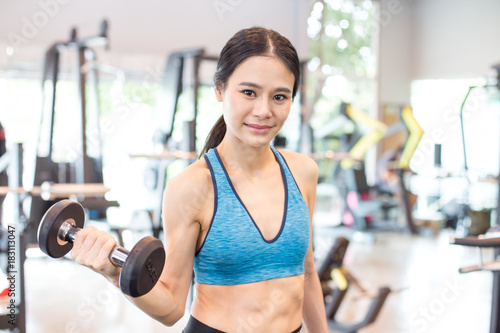 Portrait of Attractive young Asian Woman holding dumbbell in a Fitness Club.