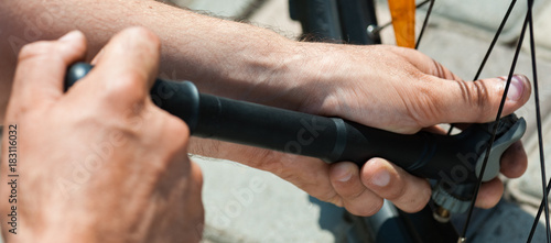 Panorama of side view of Man pumping bicycle tyre outdoors, close-up of hands