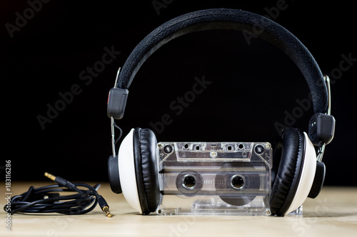 Cassette tape and headphones for listening to music. Old good music from the 80s. Wooden table.