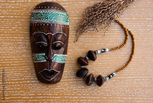 African mask with necklace and decorative branch. Tribal jewelry.