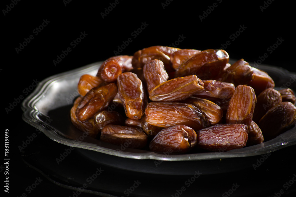 Sweet dessert dried date in old tin bowl, low key, dark theme, on black background with reflection