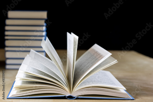 Heap of books reading on a wooden table. Beside lies . Black background.