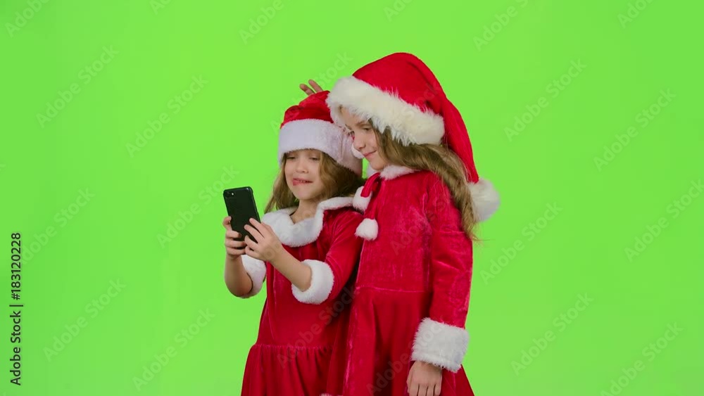 Children little ones show the tongue and make faces and make selfies on the smartphone. Green screen Children little ones show the tongue and make faces and make selfies on the smartphone. Green screen