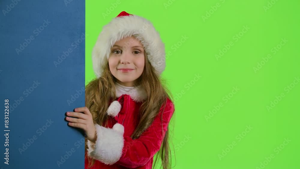 Child girl peeking out from behind the blue board. Green screen Child girl peeking out from behind the blue board. Green screen