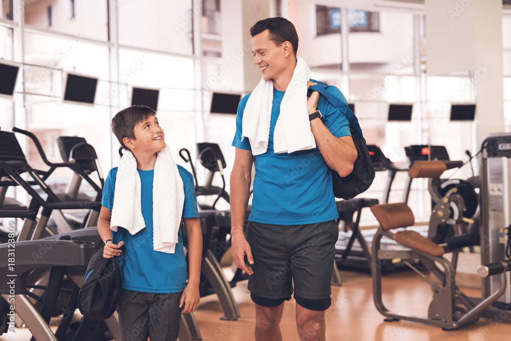Dad and son in the same clothes in gym. Father and son lead a healthy lifestyle. Dad and son in the same clothes in gym. Father and son lead a healthy lifestyle.