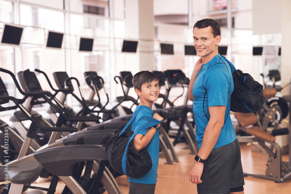 Dad and son in the same clothes in gym. Father and son lead a healthy lifestyle. Dad and son in the same clothes in gym. Father and son lead a healthy lifestyle.