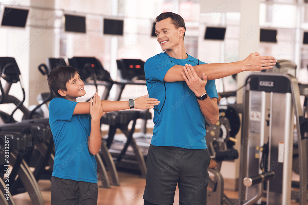 Dad and son in the same clothes in gym. Father and son lead a healthy lifestyle. Dad and son in the same clothes in gym. Father and son lead a healthy lifestyle.
