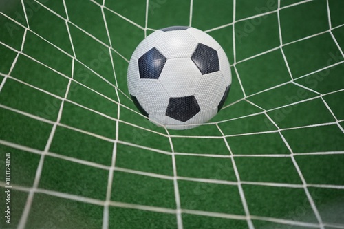 Football in goalpost against artificial grass