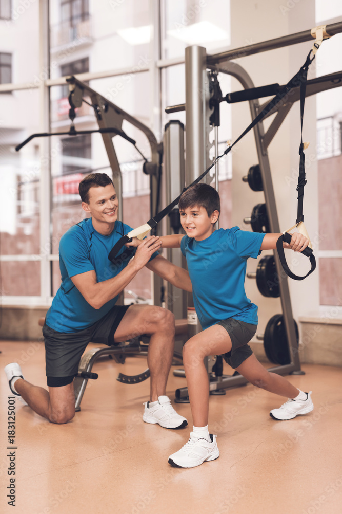 Dad and son in the same clothes in gym. Father and son lead a healthy lifestyle. Dad and son in the same clothes in gym. Father and son lead a healthy lifestyle.