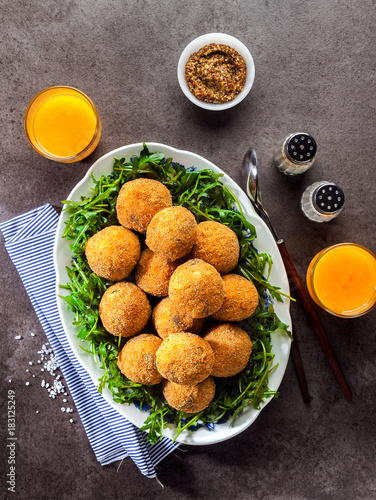 Italian snack. Fried balls from rice Arancini with mushrooms, cheese with mustard sauce and a salad of rucola on a gray stone table with freshly squeezed orange juice. fast healthy hearty meal