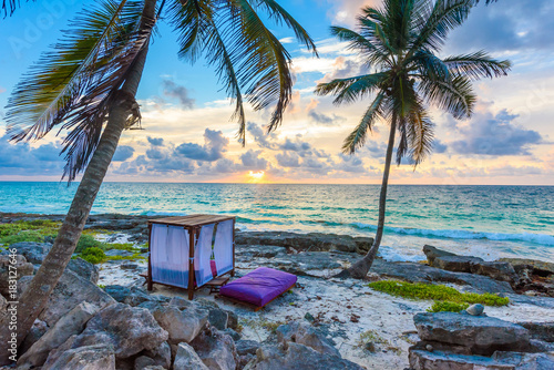 Fototapeta Naklejka Na Ścianę i Meble -  Sunset at paradise beach - Chairs under the palm trees on beach at tropical Resort. Riviera Maya - Caribbean coast at Tulum in Quintana Roo, Mexico