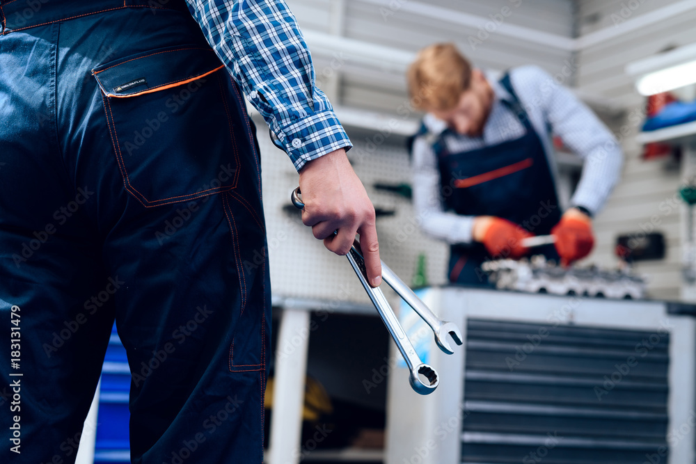 The mechanic in the auto service is standing with the instrument. Close-up photo of a mechanic's hand with a wrench The mechanic in the auto service is standing with the instrument. Close-up photo of a mechanic's hand with a wrench