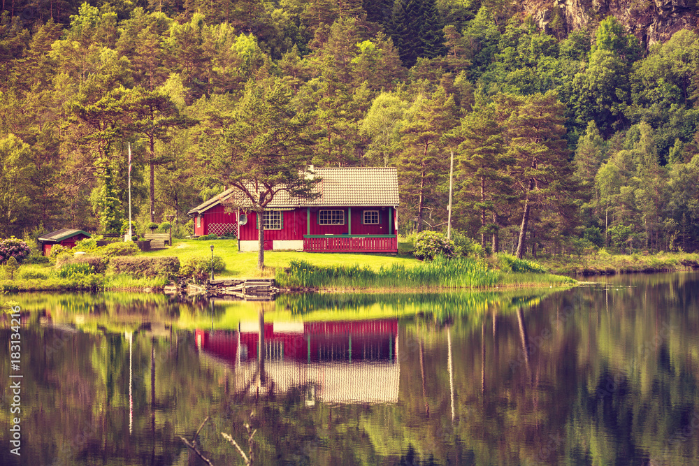 wooden cabin in forest on lake shore, Norway