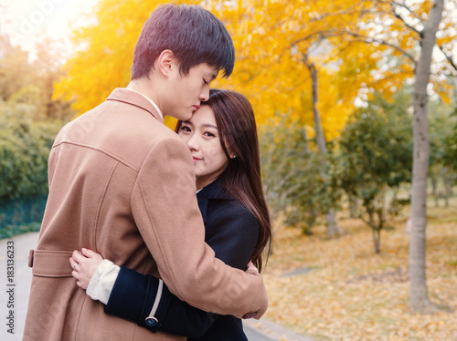 Chinese young man and woman hug and stand together with emotional expression, lover concept.