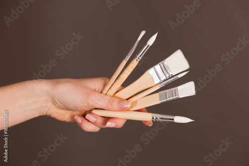 Hands holdinh brushes over dark gray background photo