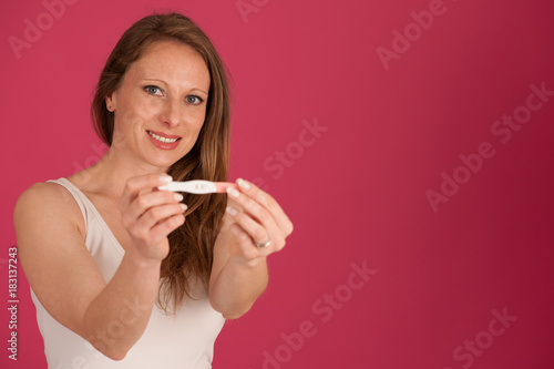 Happy woman with pregnancy test isolated over pink background