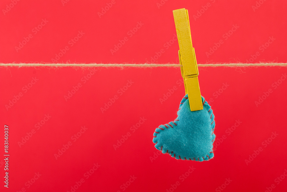 Blue heart fabric hanging on clothesline and red background with space