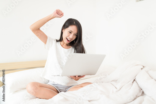 Excited woman using notebook computer