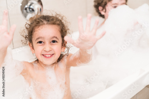 Happy child in bath covered with bubbles