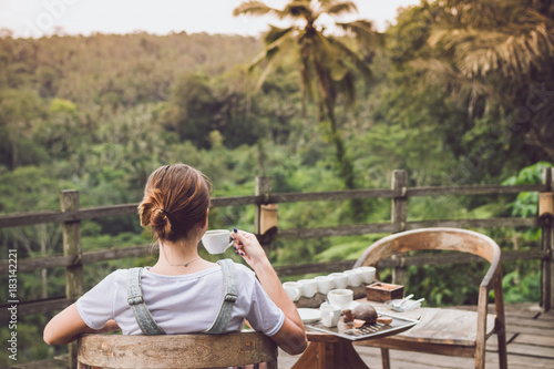 Young woman coffee tasting during sunset in the jungle rainforest of a tropical Bali island.