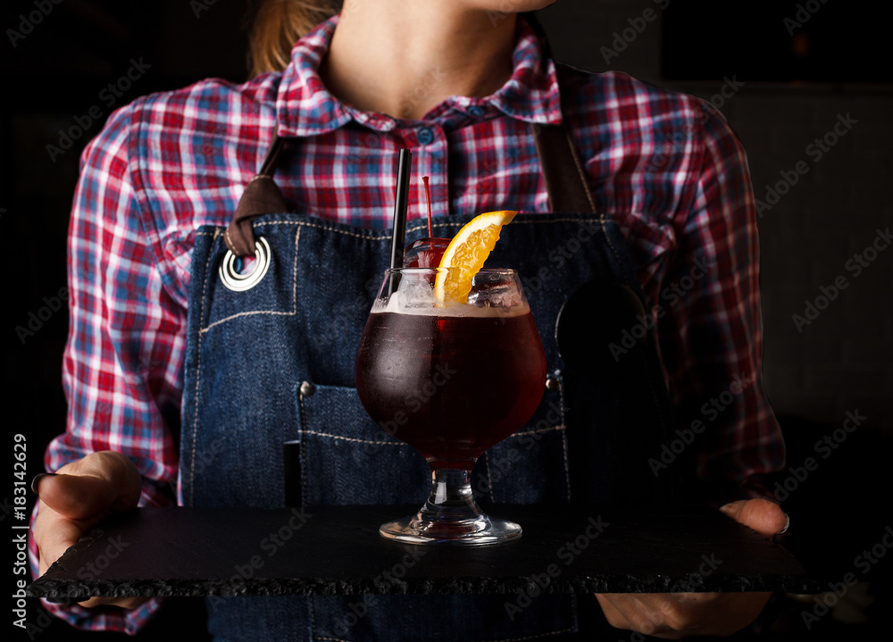 Girl waiter holds an alcoholic cocktail