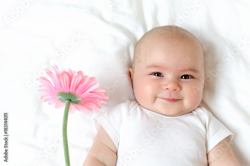 Fotografiet Baby girl holding a flower on her bed