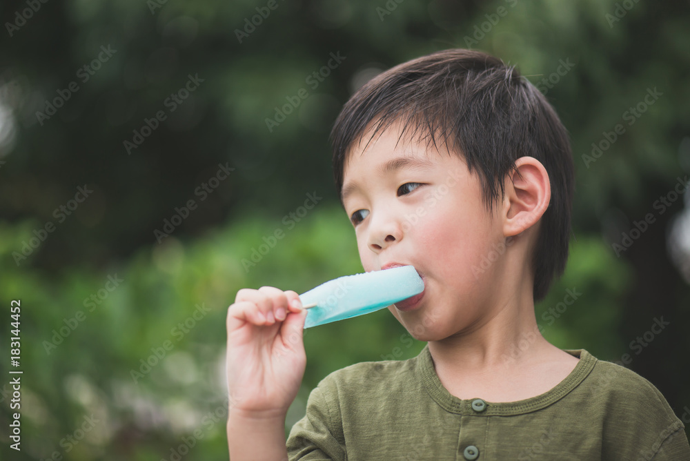 Cute Asian child eating blue ice cream outdoors Cute Asian child eating blue ice cream outdoors