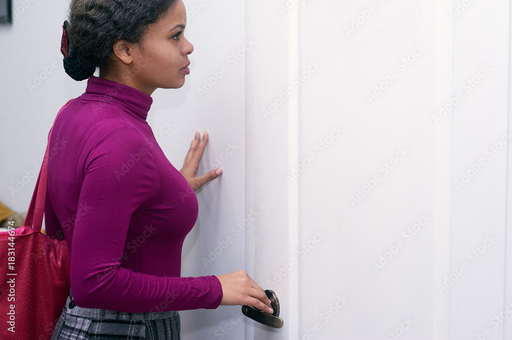 Young African woman standing at the closed door Young African woman standing at the closed door