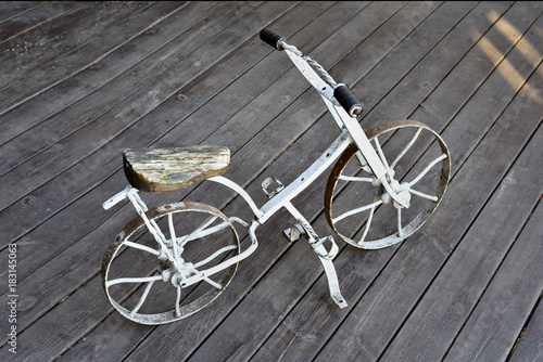старый металлический велосипед стоит на деревянной площадке и ржавеет