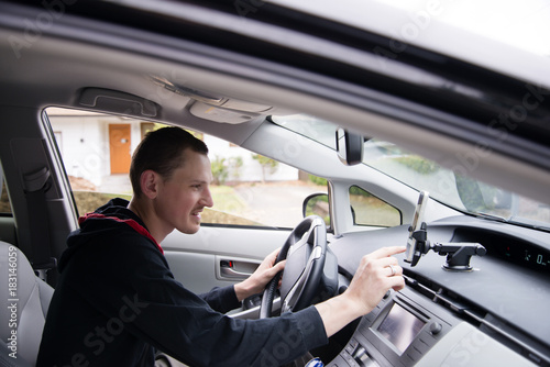 Driver sets GPS navigator sitting behind the wheel © vit